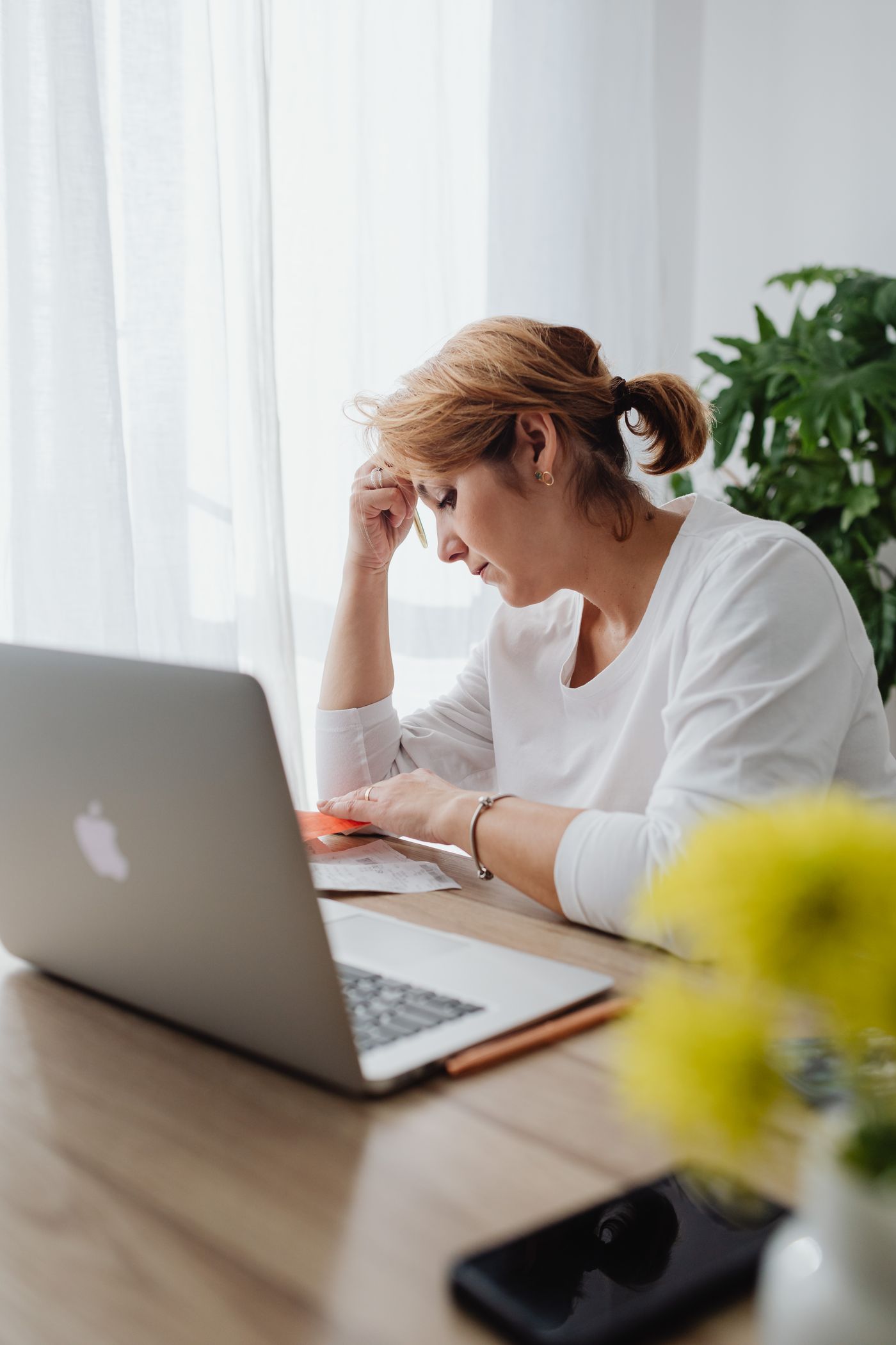 A woman pauses at her laptop, hesitant about the personal details a form is asking for